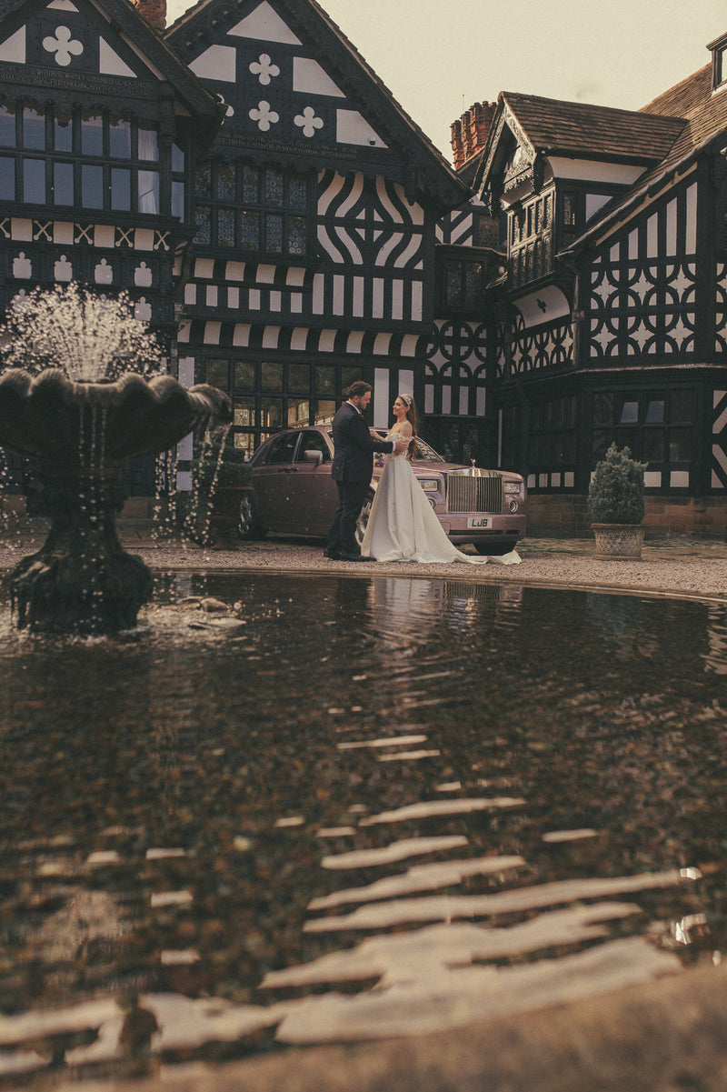 Bride and groom beside a Rolls Royce at a Tudor wedding venue