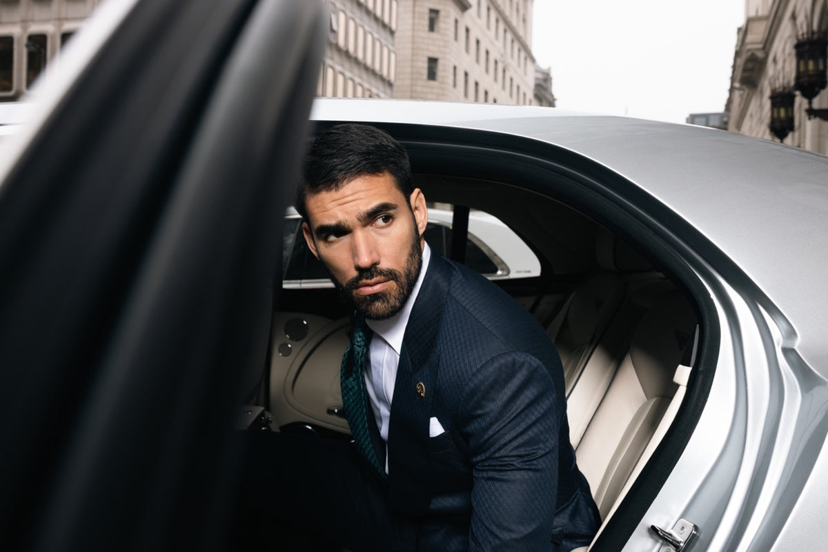 Man wearing a navy bespoke suit stepping out of a car