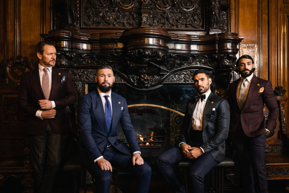 Four men in bespoke suits and eveningwear posed before an ornate fireplace