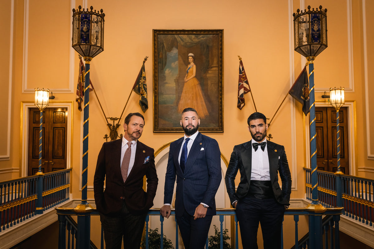 Three men in tailored suits standing in a formal hall