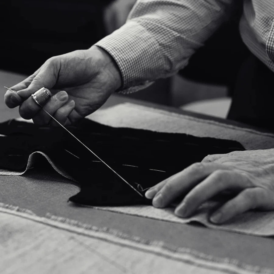 A tailor cutting cloth by hand for a bespoke commission